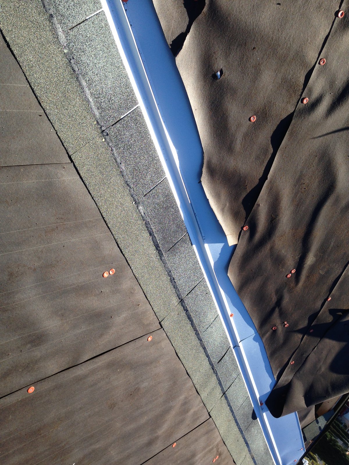 Metal drip edge along the roof edge with shingle starter on one side and underlayment lapped over the flange.