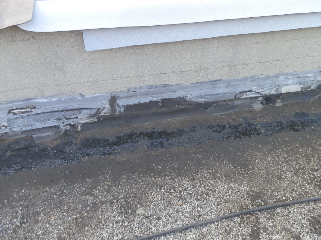 New flashing membrane at the base of a flat-roof parapet wall.