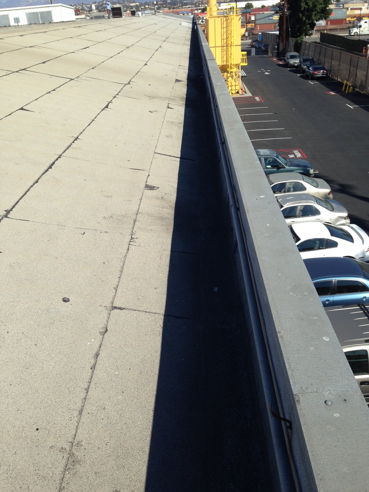 Long parapet wall with a metal cap running along the edge of a flat commercial roof.