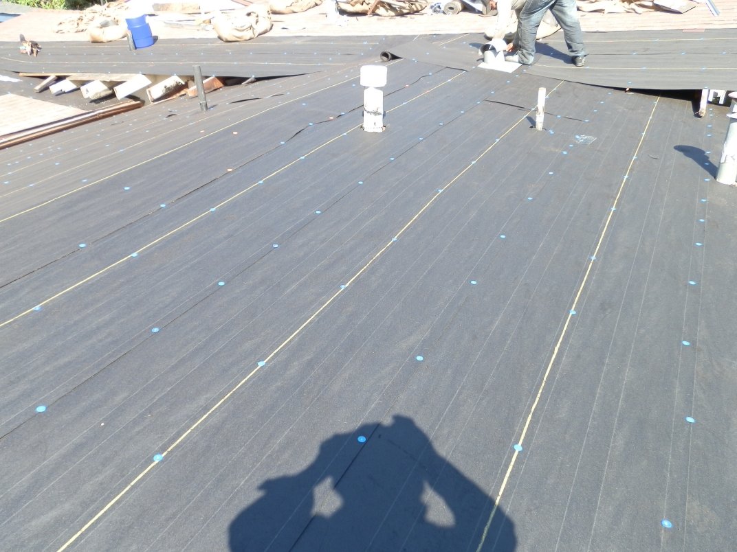 Roof deck covered in gray synthetic underlayment with fastener lines.