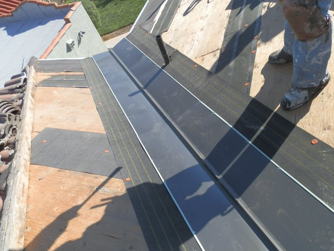 Metal-lined valley where two roof slopes meet, with underlayment on the deck.