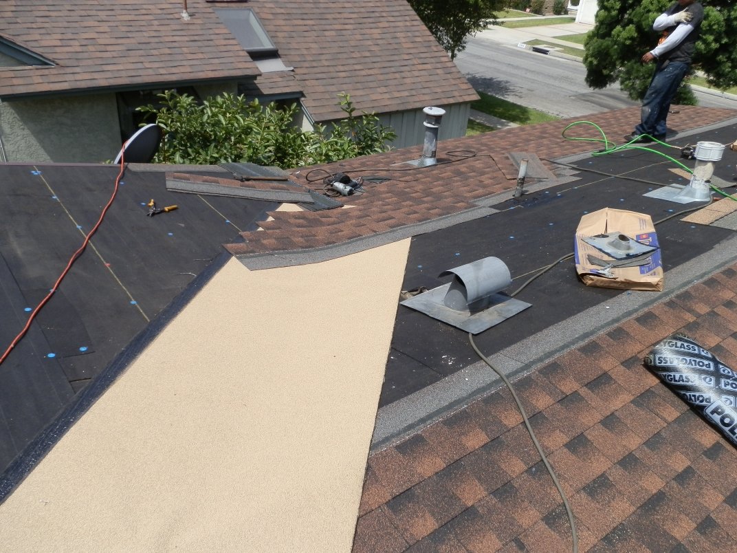 Pipe vent with flashing on a roof being re-covered with new shingles.