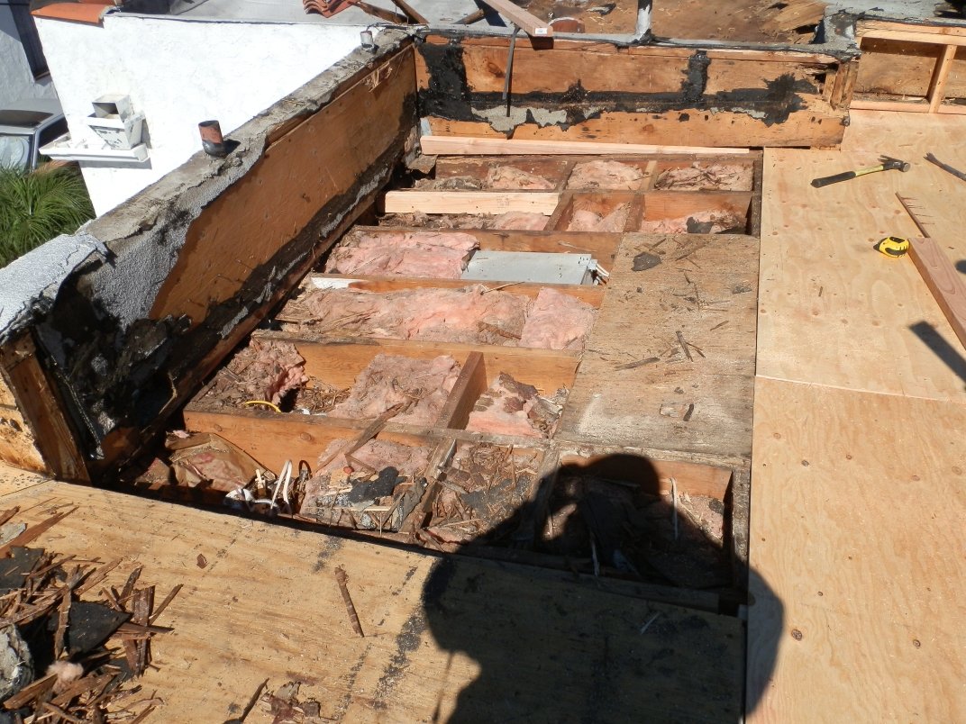 Roof sheathing being replaced with new plywood on a residential flat re-roof in Walnut Park.